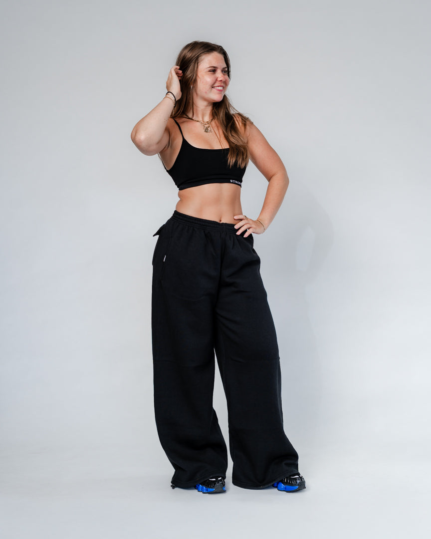 Vores Wide Leg Sweatpants kombinerer afslappet komfort med moderne design. Med et oversized fit falder bukserne flot og giver et casual look. Bukserne har baglommer med et subtilt embossed logo, der tilføjer et eksklusivt touch. Bukserne har snøre i taljen for en justerbar pasform – og snørerne i anklerne giver dig mulighed for at style dem, som du vil: lad dem hænge løst for det klassiske wide leg-look, eller snør dem ind for et mere tapered udtryk.