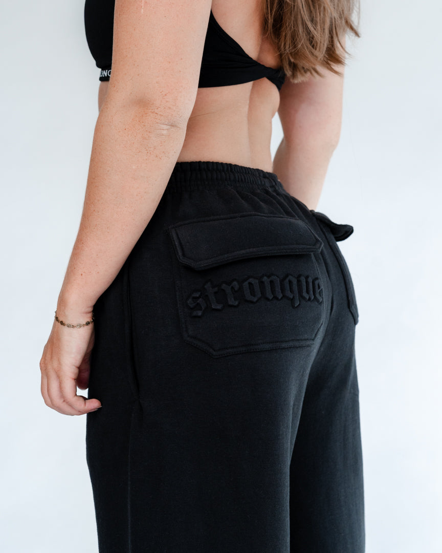 Vores Wide Leg Sweatpants kombinerer afslappet komfort med moderne design. Med et oversized fit falder bukserne flot og giver et casual look. Bukserne har baglommer med et subtilt embossed logo, der tilføjer et eksklusivt touch. Bukserne har snøre i taljen for en justerbar pasform – og snørerne i anklerne giver dig mulighed for at style dem, som du vil: lad dem hænge løst for det klassiske wide leg-look, eller snør dem ind for et mere tapered udtryk.